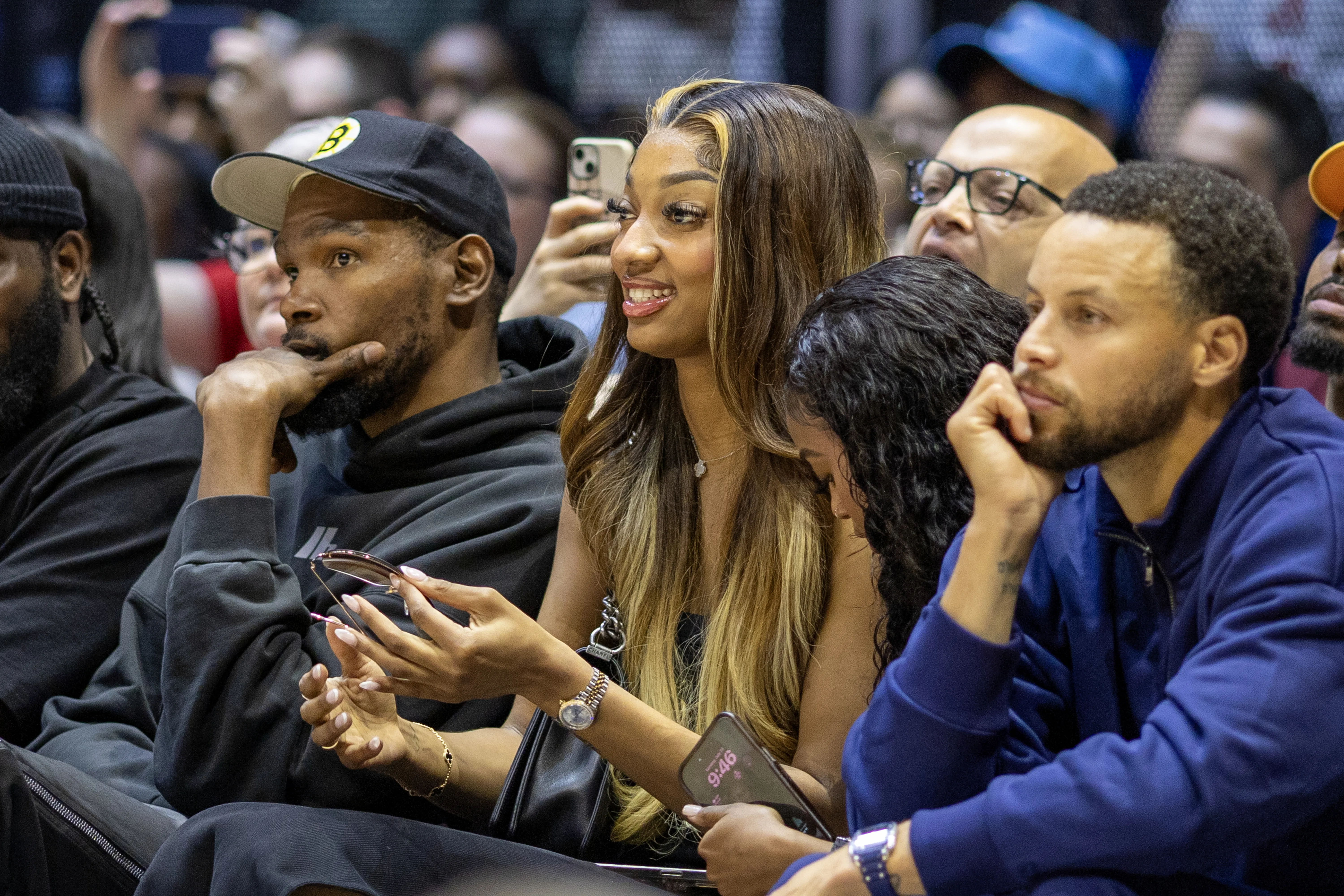 Kevin Durant, Angel Reese, and Stephen Curry watching a women's basketball match.